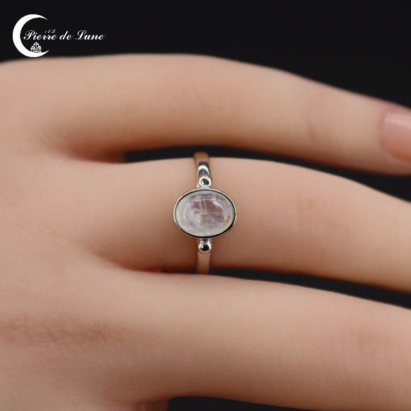 Gros plan sur la pierre de lune blanche naturelle polie de la Bague chic (Astraé).