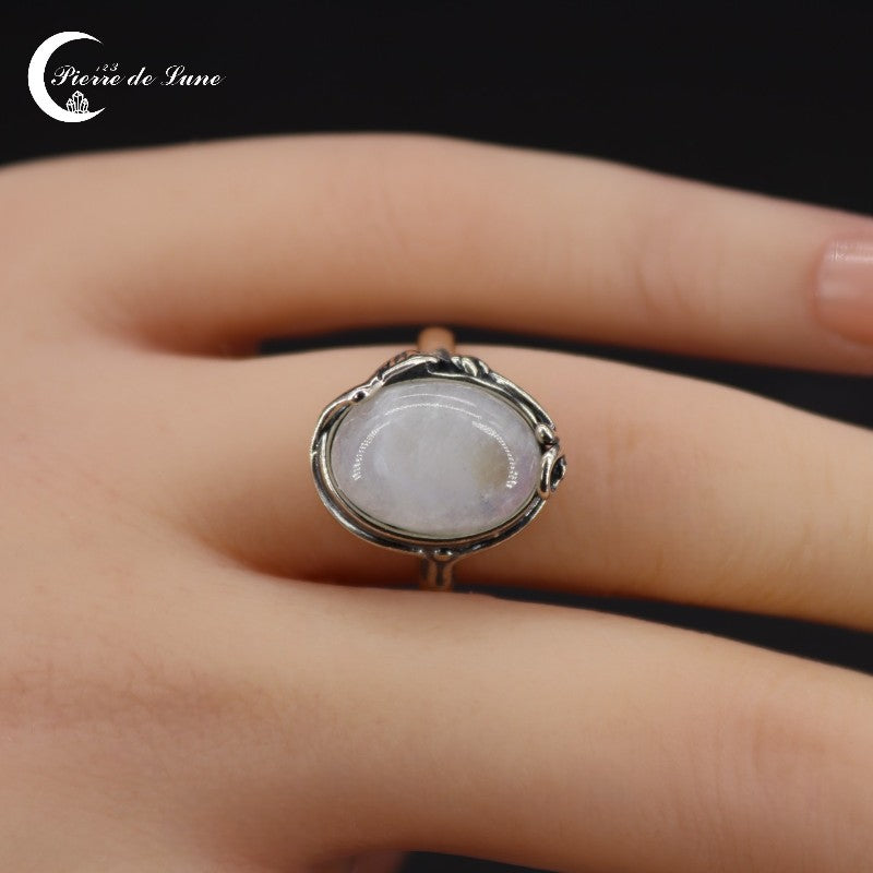 Gros plan sur la pierre de lune polie de la Bague (Kyrene) révélant ses reflets sur monture argent.